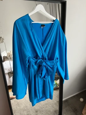Blå Klänning - En superfin blå sommarklänning från Gina tricot som är använd 1 gång och är som i nyskick. Passar typ alla kroppar tack vare knytbanden som gör att man själv bestämmer hur stor den ska vara. Jag är en M i klänningar i vanliga fall. 