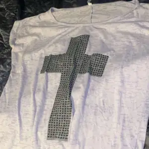 En fin T-shirt med tryck på av ett kors och med fina svarta stenar på. Den är nästan  ny och i ett bra skick. 
