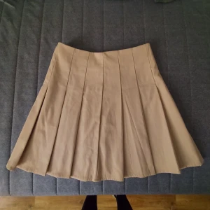 Plisserad kjol - Beige plisserad kjol med dragkedja bak. Stl s