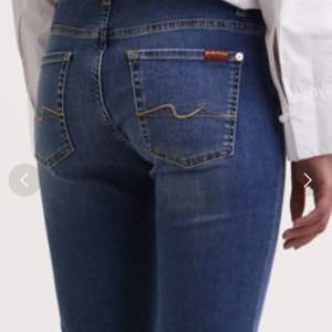 Blå jeans med gula stickningar på bakfickor. Stl 26, lågmidjade, bootcut. Ben innerlängd 80 cm. Märke ”For all mankind”.