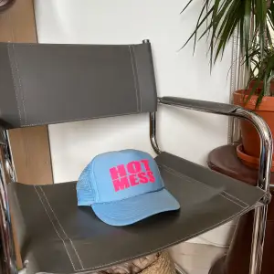 trucker hat in baby blue with pink text saying “hot mess”.   bought in the USA a couple of years ago. few signs of wear but nothing major