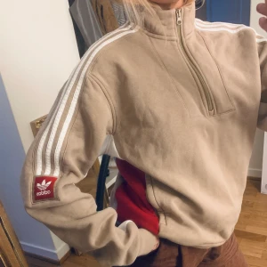 Adidas-tröja, beige zip-up i strl S - En gammal favorittröja med dragkedja som inte kommer till användning längre. Snygg beige färg ihop med de vita ränderna.  Är lite oversize på mig som är S då det är en herr-Small.