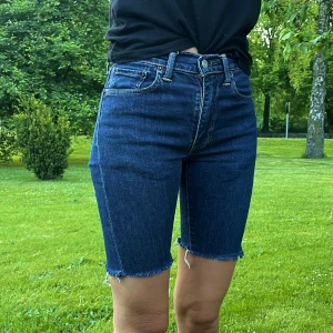 Levis shorts  - Ett par mörkblåa Levis shorts i längre modell och är lite lägre i midjan. Använda men i bra skick! Storleken säger 30 i midjans storlek men jag har 26 i midjan och de passar fint på mig. 💙