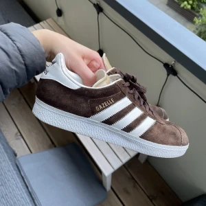 Adidas Gazelle Sneakers - Nästan helt nya Adidas Gazelle (använda max 10 gånger) i brun mocka! Assnygga men sitter inte så bra på mig⭐️storlek 40, nypris 1099kr🤞