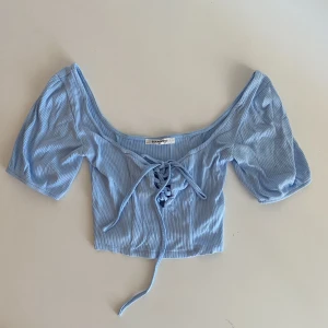 Ljusblå topp - Knappt använd blå crop top med knyt. Inte genomskinlig, fint tyg. Storlek 34 men stretchig, passar 36 (som jag har, se bild 2) och säkert större *ੈ✩‧₊˚༺☆༻*ੈ✩‧₊˚
