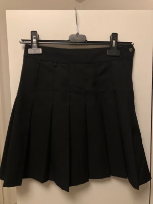 Svart veckad kjol - Säljer denna svarta A-linje kjol från H&M. Väldigt fin och passar till mycket. Perfekt nu till hösten^^ Finns två öglor på vardera sida av kjolen där man kan hänga något💗 Kontakta vid frågor eller intresse! Frakt betalas av köparen