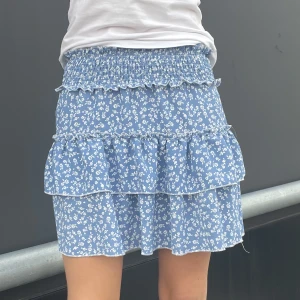 Blå kjol - Blå kjol med små vita blommor som mönster, perfekt för sommaren. Polyester