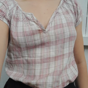 Rutig blus - Kort härligt rutig hunkydory-blus med v-ringning och broderier fram och bak. Har använts ett par gånger samt har en figurnära passform.