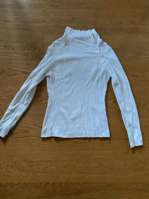 Polotröja med knappar - Fin polotröja med y2k känsla och knappdetaljer. Knapparna går att knäppa upp för att få gragen att ligga ner. Har använts men är inte sliten. 