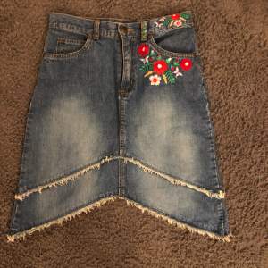 En lite längre jeans kjol med väldigt fina och unika blom detaljer både bak och fram