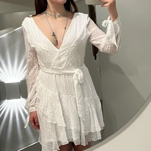 Vacker vit klänning från Dennis Maglic  - Söt klänning som sitter superfint på! Den har aldrig använts. Den är normal i storleken. Den har dubbla lager tyg förutom på armarna