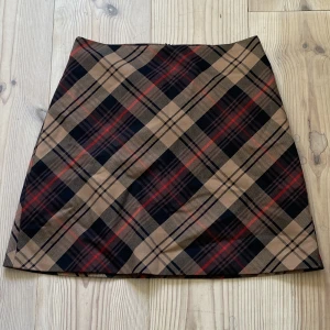 Rutig kjol  - Säljer en jättefin minikjol i rutigt tyg! Den är endast använd en gång och är i mycket bra skick. Sitter högmidjat på mig som har strl. M, men kan nog sitta mer åt det lågmidjade håller på personer med strl. XS-S!!