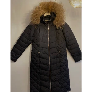 Lång vinterjacka med äkta pälskrage - Svart lång vinterjacka med äkta pälskrage från Holly. Mycket bra skick, använt 2 ggr.