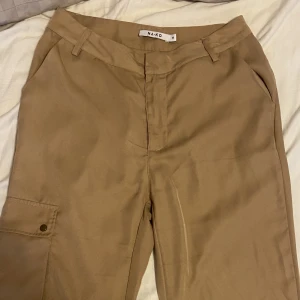 beige cargo  - Super fin och unik cargobyxor från NA-KD som är beige i storlek 36. Formar kroppen så snyggt använd 2 gånger!!🩷
