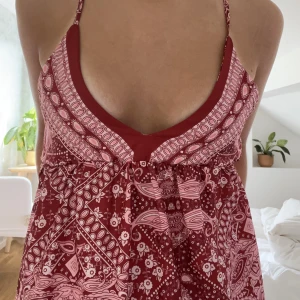 Röd lång Ibiza klänning  - Röd och vit mönstrad långklänning som går perfekt ner till fötterna på mig som är runt 165. Smickrande åtsittande runt byst. Köpt vintage i Spanien och redan omsydd vid köp, inga märkbara skador, utan enbart synliga sömmar inifrån. Justerbara axelband❤️