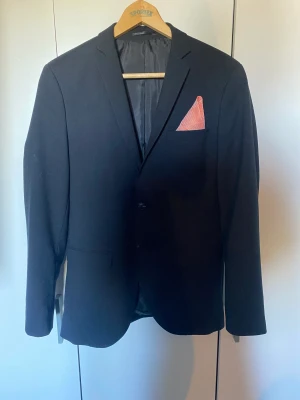 Kostym  - Kostym som är använd endast på avslutningen i 9an. Kavaj i storlek 46 herr  Kostymbyxor i storlek 48 herr  Fluga och näsduk ingår.