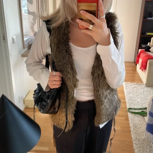 Brun Pälsväst - Säljer denna bruna pälsvästen, fake fur. Läderrem rem. Finns två spännen att knäppa den i. Tveka inte att fråga om fler bilder eller något annat! Köparen står för frakt 🚚💗