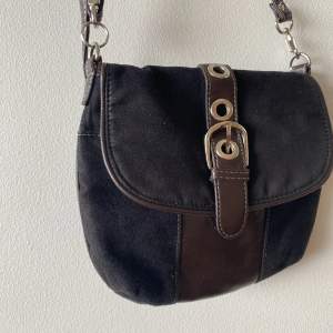 Vintage handväska i mocka och läder-imitation. Brun och svart. Tyvärr litet hål under fästet men syns inte när väskan är stängd. 