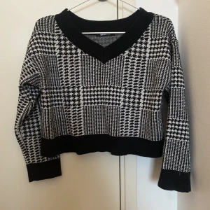 Stickad tröja från H&M - Cropped stickad tröja med V-ringning och snyggt mönster.
