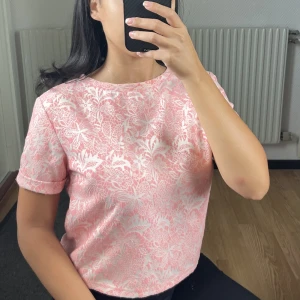 Jättefin rosa/vit topp - Rosa topp med vitt ”tryckt” mönster och korta ärmar. Har en dragkedja i nacken 💖  Storlek XS men passar även S 