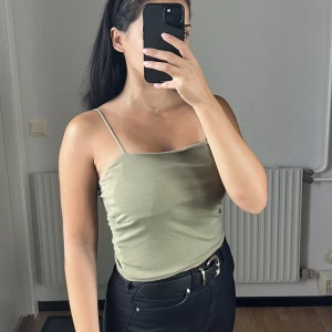 Militärgrön topp - Militärgrön topp med tunna band köpt på Gina Tricot. Har dubbla tyger runt bysten. Är i storlek M men passar även S 💚
