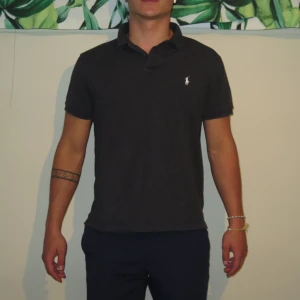 Polo Ralph Lauren Piké  - Hej! Säljer denna jätte fina piké från Polo Ralph Lauren.  Den är mörk grå i färgen.  Storlek L men sitter som M. Jag är 178 och väger 74 kg, och den sitter perfekt! Con 10/10 sparsamt använd,inga som helst tecken på slitage!  Hör av dig vid fler frågor !