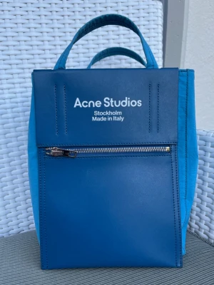 Acne Studios Nylon Papery Bag - Härligt blå liten totebag från Acne Studios.   Jättefint skick! Använd ca 5 ggr.  Butikspris 4400:- Köpt i Sthlm. Kvitto och dustbag finns. 
