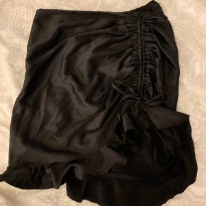 Svart kjol  - Band på ena sidan som går att ändra längden på. 