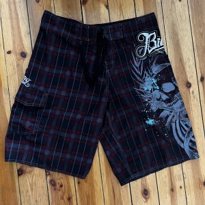 Billabong shorts - Coola y2k shorts! De är svart- och rödrandiga med ett stort klassiskt billabong-tryck på sidan. Tyget påminner om badbyxor men jag vet inte om det faktiskt är det. De är stora och passar bra som oversized för de flesta. Skriv vid frågor eller exakta mått!