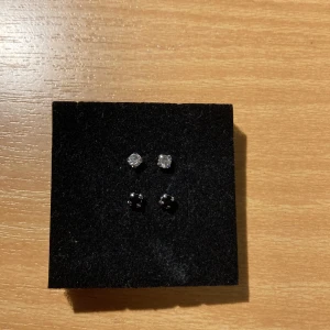 Örhängen  - Örhängen med små stenar på, köpta i Korea. Svarta och vita. Aldrig använda och helt allergifria!  10kr för ett par  15kr för båda 