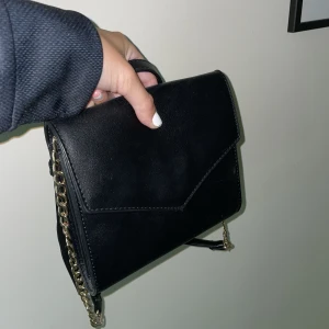 Axelremsväska - En svart guldig axelremsväska 