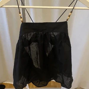 Topp från Zara - En mörkblå/svart topp från zara med knyte i ryggen och pärlor på banden i fint skick utan några fläckar eller hål och endast använd ett fåtal gånger