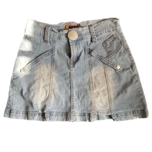 Jeanskjol med detaljer - Så söt jeans kjol med så fina detaljer! Står strlk L men skulle säga mer som S ksk? Midjemåttet är iaf 38cm ( mätt rakt över) inte sätt några defekter. ( solen ville kika in på vänstra sidan av kjolen )