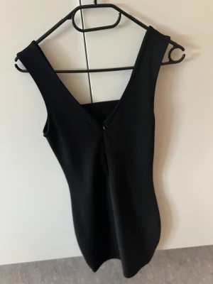 Svart klänning  - Svart klänning från Nelly med dragkedja där bak och en öppning nedanför brösten. Superfin festklänning! Sparsamt använd.