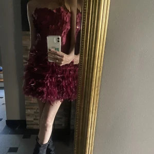 Vinröd klänning  - Unik vinröd klänning med fjädrar. Passar på mig med XS men även S!