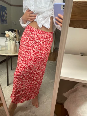 Röd- och vitblommig kjol - Sval blommig kjol med vita blommor. Har en liten slits på ena benet.   Superfin med linneskjorta eller ett vitt linne🥰