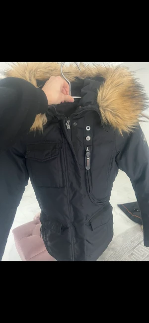 Hollies jacka  - Modellen är Hollies subway.  Köpt för något år sedan på Nellys hemsida . Nupris 3950kr Storleken är 36 men passar 38 också. Går att justera i midjan. Jackan är i ett gott skick.  Den är tung och håller dig varm.  PÄLSEN ÄR INTE ÄKTA! 