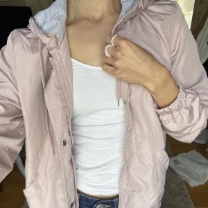Vårjacka H&M - Tunn vår/träningsjacka från H&M i gammelrosa färg. Luvan är klädd i grå bomull. Har både dragkedja och knappar, samt dragsko både nertill och i halsen. Aldrig kommit till användning då det var ett impulsköp. Utan defekter😊