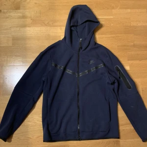 Nike tech fleece  - Nike tech fleece tröja i marinblå storlek m. Superfin och knappt använd. Liten fläck på vid ena armbågen men inget som syns på långt håll, går förmodligen bort i tvätten. 300kr+frakt