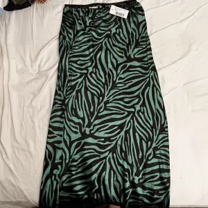 Grön zebramöstrad kjol från NELLY. Aldrig använd med lapp kvar! Den är i silke och har en slits där bak så det är enkelt att röra sig i den👍 