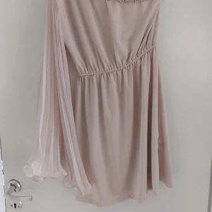 Festklänning - Fin enarmad klänning med vacker dekor i halsringningen hela vägen runt. Superfint skick från ett rök och djurfritt hem.