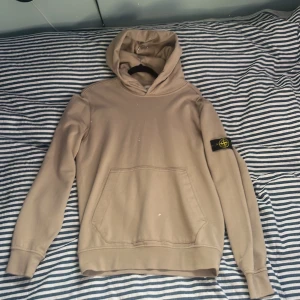 Stone Island Hoodie Beige - En stone island hoodie i färgen beige. Storlek 170/14. I nyskick använd fåtal gånger. Kvitto finns från NK i Stockholm. Köpt ny för 1900.