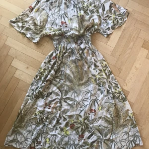 Klänning - En lätt och super fin klänning i ett mjukt tyg perfekt för sommaren! Den är lös runt benen och armarna men har resor i midjan. Storlek S men passar M-L