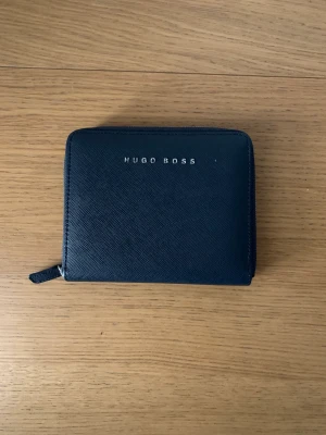 Hugo Boss Handväska  - Nu är det dags för mig att sälja min Hugo Boss hand väska. Ja har haft väskan i cirka 5 månader men har tyvärr inte hitta tillfälle till att använda den. Har inget behov av den därför vill ja sälja den.