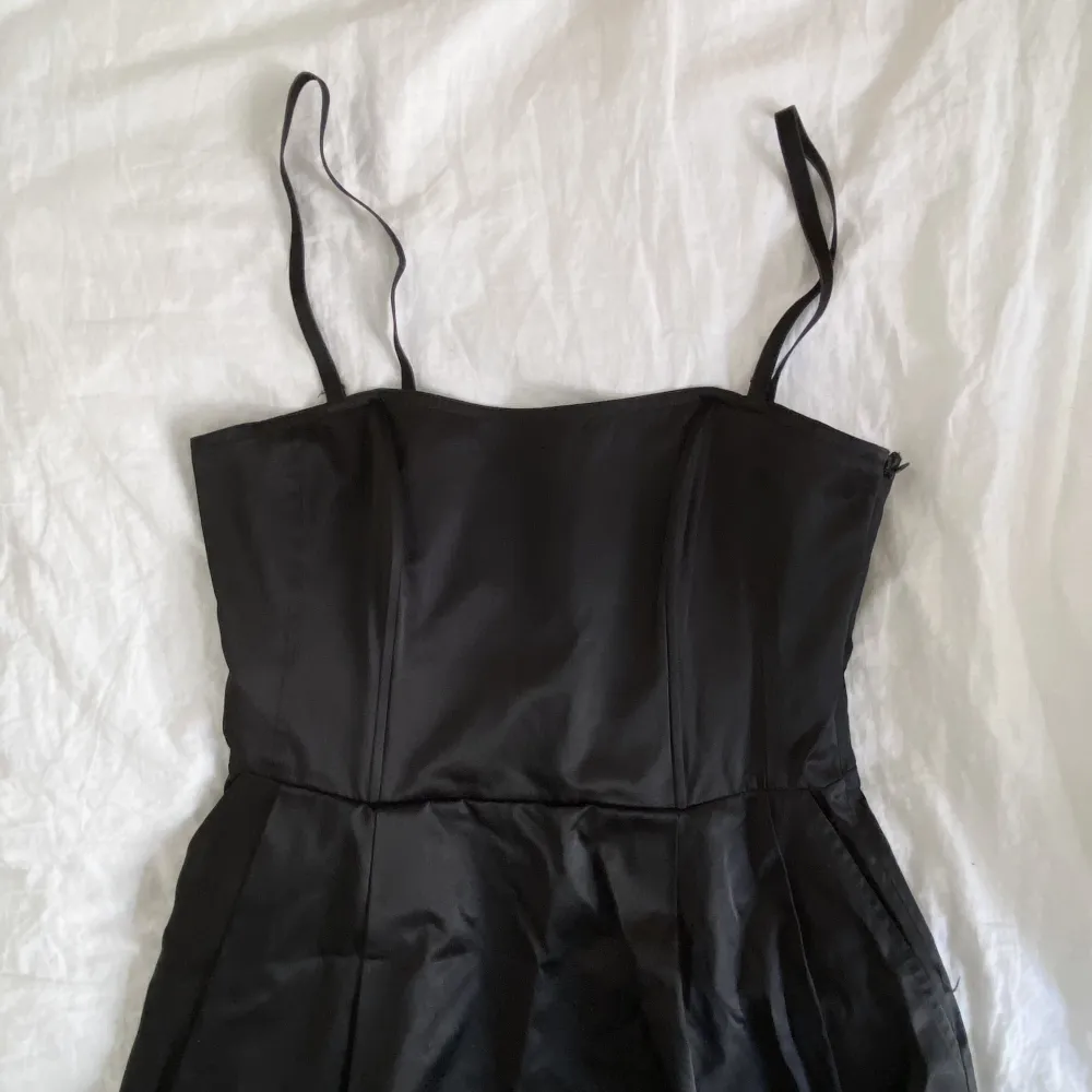 En superfin svart klänning i blankt satinliknande tyg. Klänningen är köpt via Sellpy men jag har själv satt ditt axelband (som man kan ta av). Den har en dragkedja i sidan. I fint skick!. Klänningar.