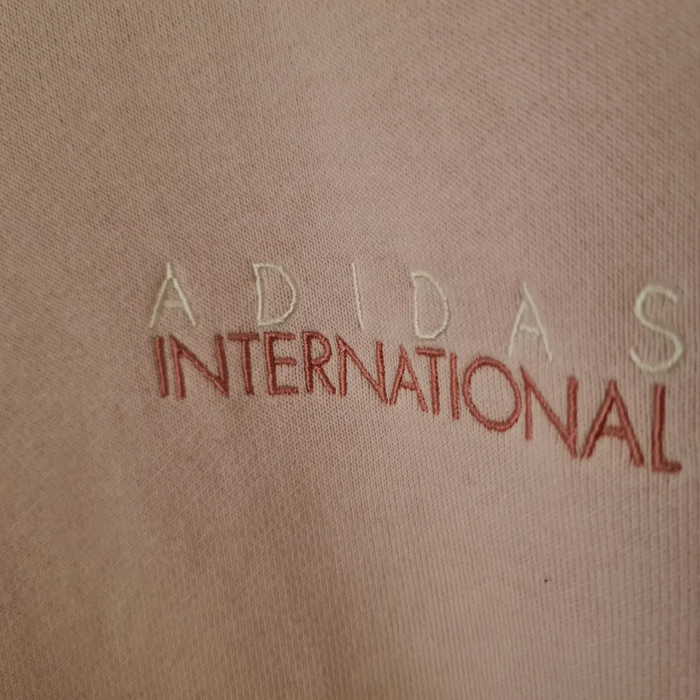 En rosa Adidas International Hoodie i storlek Large. Den är i bra skick och bara använd ett par gånger.. Hoodies.
