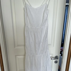 Vit långklänning med knytning i ryggen - Säljer denna oanvända klänning från & Other stories. Broderat mönster och justerbar knytning i ryggen. Prislapp finns kvar, ordinarie pris 1300