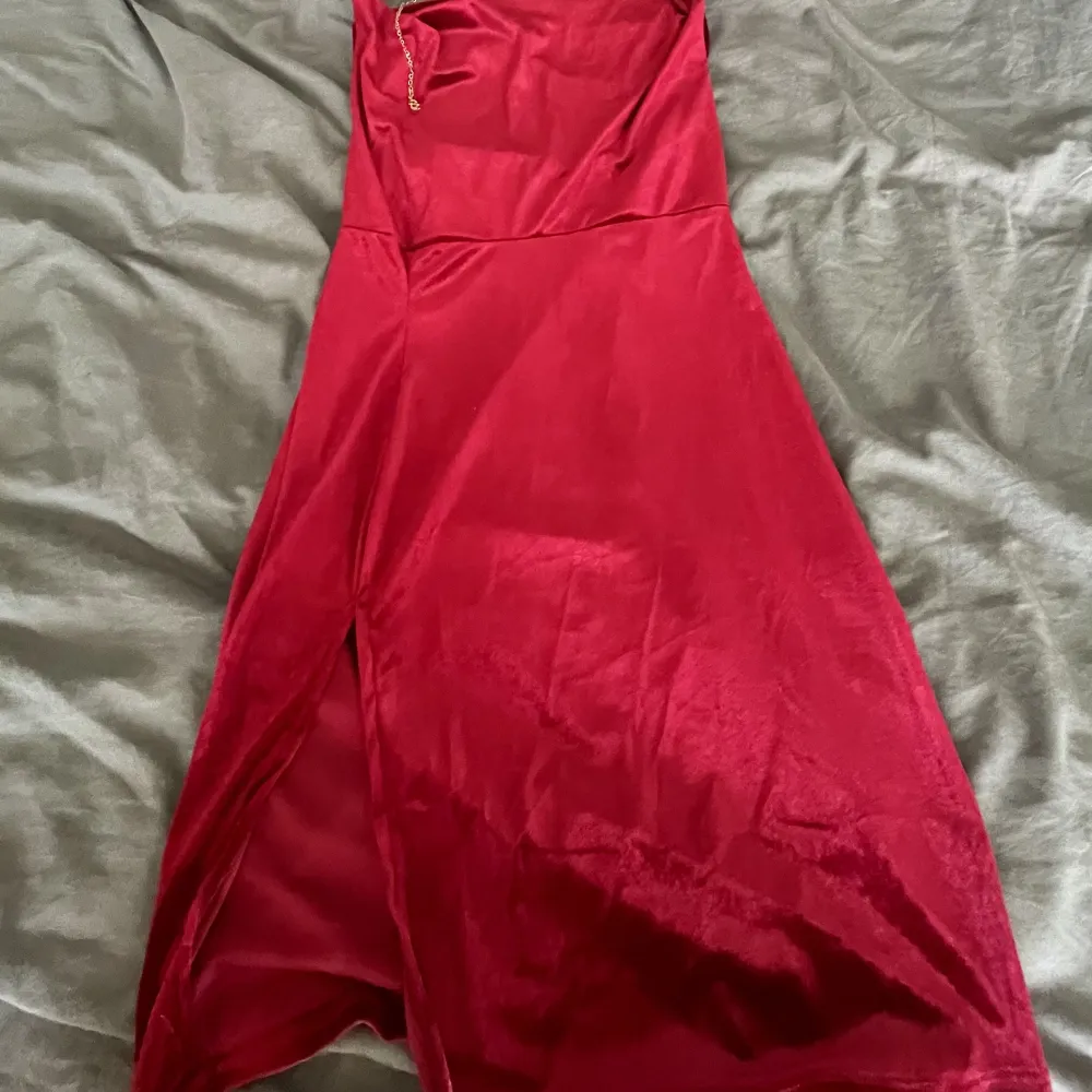 Röd halvlängds mini/midi klänning med velvet textur från FashionNova. Den har en guldkedja som band runt halsen med en super gullig liten kristall detalj som hänger ner över ryggen/axeln. Den är helt ny med tagg fortfarande kvar. Klänningar.