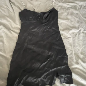 Svart mini klänning  - Svart mini klänning med jättefina kristallband och en liten knytdetalj vid bysten. Den kommer från Pull&Bear och är i storlek M