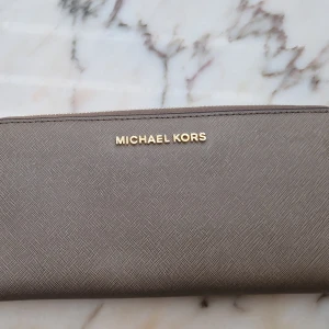 Michael kors plånbok - Säljer en plånbok från Michael kors i måtten 21cmx11cm. Nyskick knappt använd.
